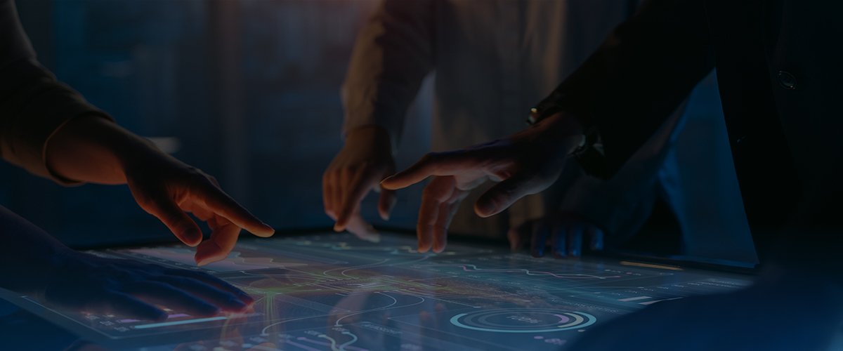 Several hands working on a tabletop touchscreen computer
