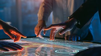 Several hands working on a tabletop touchscreen computer