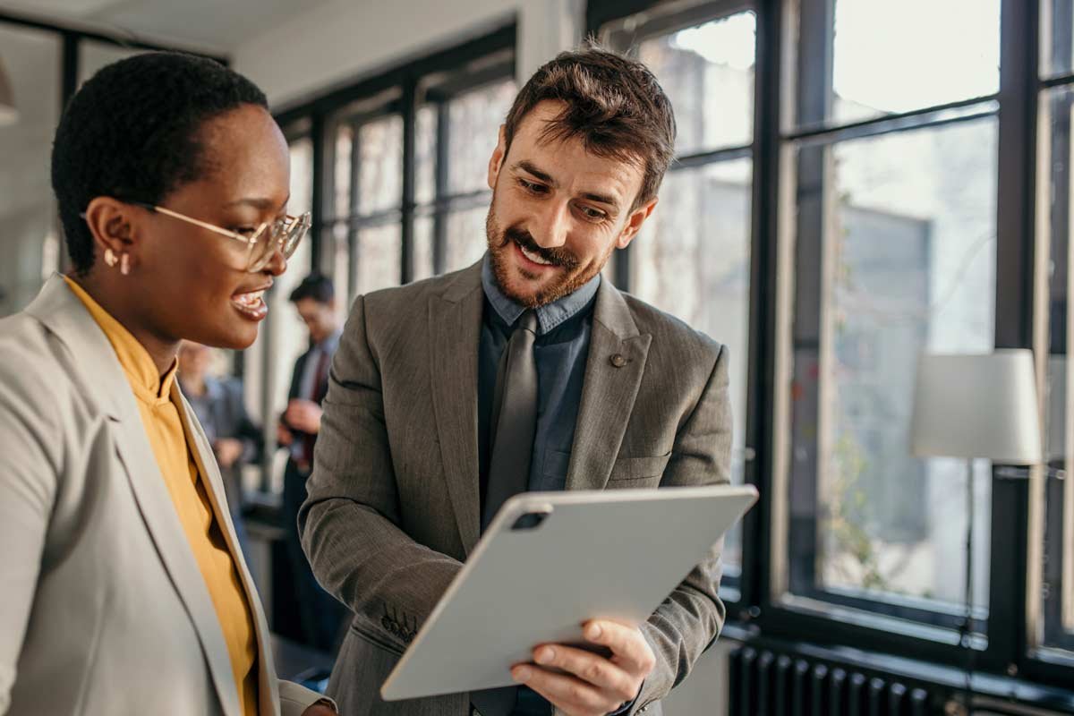 man showing colleague info on a digital tablet