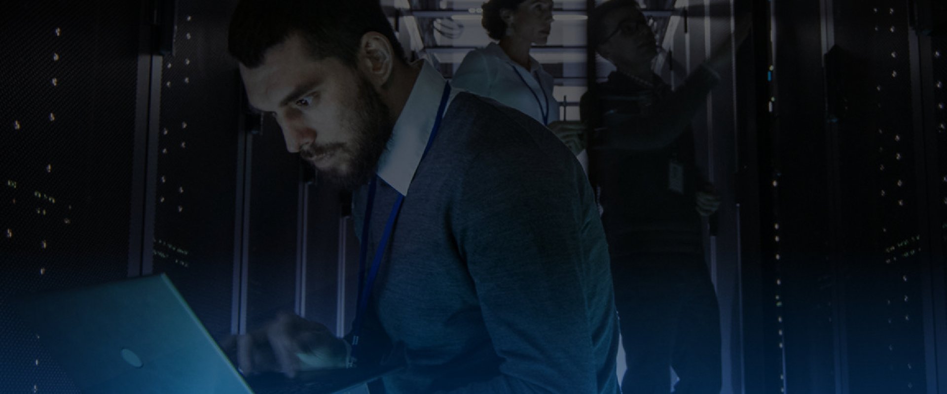 Man on laptop working in a server room